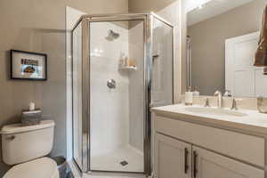 Bathroom with a shower with door, toilet, and vanity