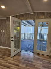 Entryway featuring beamed ceiling, wood-type flooring, wood walls, and french doors