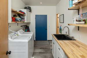 Clothes washing area featuring cabinets, dark hardwood / wood-style floors, washing machine and dryer, and sink