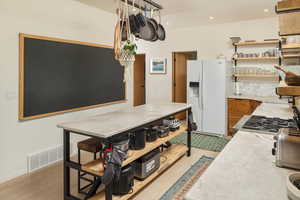 Kitchen with light hardwood / wood-style floors, white refrigerator with ice dispenser, and range