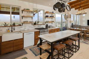 Kitchen with stainless steel stove, white dishwasher, light hardwood / wood-style floors, decorative backsplash, and sink