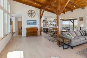 Living room featuring light wood-type flooring, beamed ceiling, wooden ceiling, and high vaulted ceiling