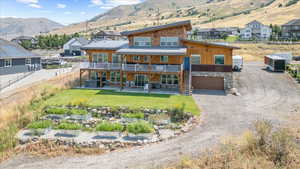 Rear view of property featuring a mountain view, a garage, a patio area, and a yard
