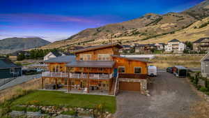 View of front of home with a mountain view, a patio area, a garage, and a lawn