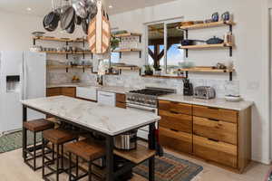 Kitchen with decorative backsplash, sink, white appliances, and light wood-type flooring