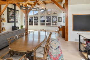Dining room featuring beamed ceiling, hardwood, an inviting chandelier, and high vaulted ceiling
