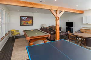 Game room featuring beam ceiling, hardwood / wood-style flooring, a wood stove, and billiards