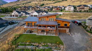 Back of house featuring a patio, a balcony, a lawn, and a mountain view