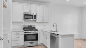 Kitchen with stainless steel appliances, light hardwood / wood-style flooring, sink, and kitchen peninsula