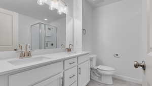 Bathroom with walk in shower, dual vanity, tile patterned floors, and toilet