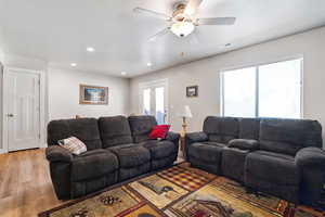 Living room with a wealth of natural light, light wood-type flooring, french doors, and ceiling fan