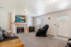 Living room featuring a textured ceiling, a tiled fireplace, and light colored carpet