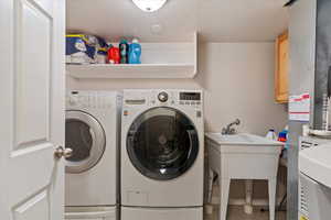 Clothes washing area featuring washing machine and dryer, tile patterned flooring, cabinets, and a textured ceiling