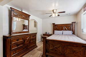 Bedroom featuring light hardwood / wood-style floors, a textured ceiling, and ceiling fan