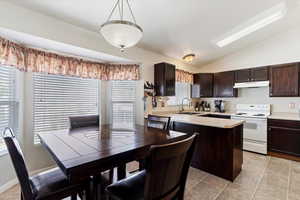 Kitchen featuring light tile patterned flooring, dark brown cabinets, white range with electric stovetop, sink, and vaulted ceiling