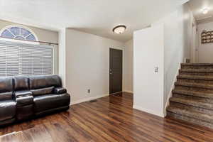 Living room with dark hardwood / wood-style floors and a textured ceiling