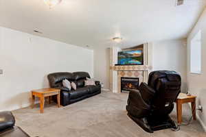 Carpeted living room with a textured ceiling and a fireplace