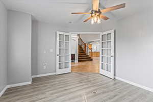 Spare room with light hardwood / wood-style floors, french doors, and ceiling fan