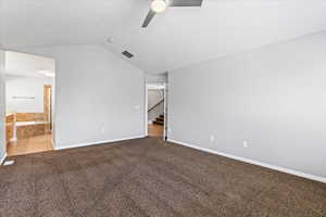 Carpeted spare room featuring lofted ceiling and ceiling fan