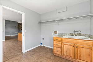 Clothes washing area with sink, hookup for a washing machine, tile patterned flooring, and hookup for an electric dryer