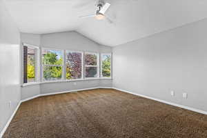 Spare room with carpet floors, ceiling fan, and lofted ceiling