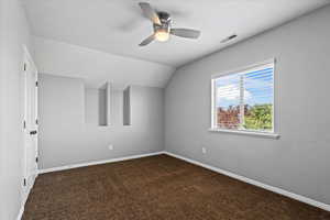 Carpeted spare room with vaulted ceiling and ceiling fan