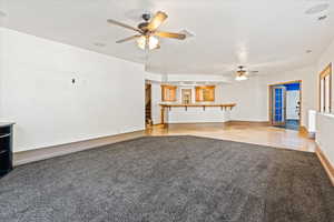 Unfurnished living room featuring light carpet and ceiling fan