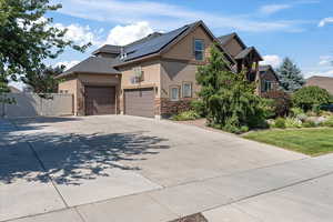 View of front of property featuring a garage, solar panels, and a front yard