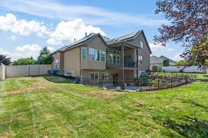 Rear view of house with a balcony and a lawn