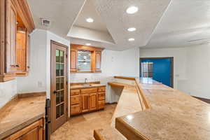 Kitchen with sink, light tile patterned flooring, a textured ceiling, and a raised ceiling