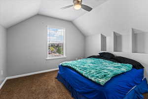 Carpeted bedroom featuring lofted ceiling and ceiling fan