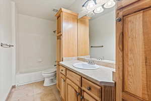 Full bathroom featuring vanity, tile patterned floors, washtub / shower combination, and toilet