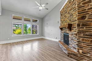 Unfurnished living room featuring high vaulted ceiling, a fireplace, ceiling fan, and wood-type flooring