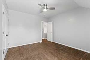 Spare room with carpet, ceiling fan, and vaulted ceiling