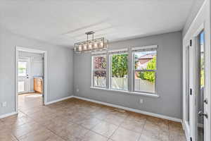 Spare room featuring light tile patterned flooring, plenty of natural light, and a chandelier