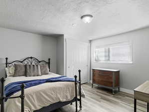 Bedroom with light hardwood / wood-style floors and a textured ceiling