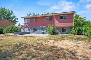 Rear view of property featuring cooling unit, a patio area, and a lawn