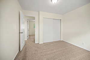 Unfurnished bedroom with carpet, a closet, and a textured ceiling