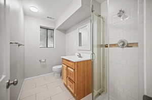 Bathroom with vanity, toilet, a shower with door, a textured ceiling, and tile patterned flooring