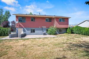 Back of property with cooling unit, a lawn, and a patio area