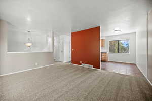 Unfurnished living room featuring light carpet and a textured ceiling