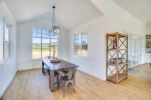 Dining area with a notable chandelier, high vaulted ceiling, and light wood-type flooring