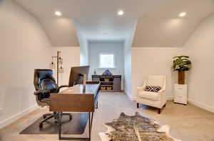 Carpeted office space with lofted ceiling