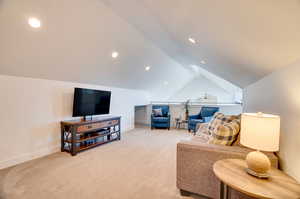 Carpeted living room featuring vaulted ceiling