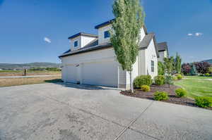 View of property exterior with a mountain view, a garage, and a lawn