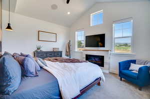 Bedroom with multiple windows, a tiled fireplace, vaulted ceiling, and carpet floors