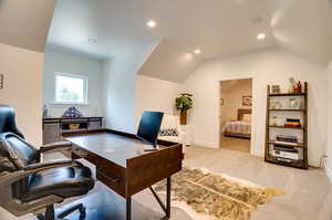 Home office with vaulted ceiling and light colored carpet