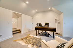 Carpeted home office featuring lofted ceiling