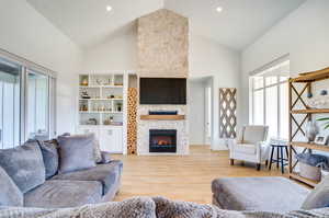 Living room with high vaulted ceiling, a fireplace, and light hardwood / wood-style floors