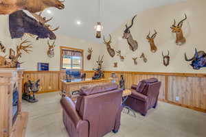 Trophy room built next to garage. Multi purpose bonus room. Carpeted space featuring wood walls and vaulted ceiling